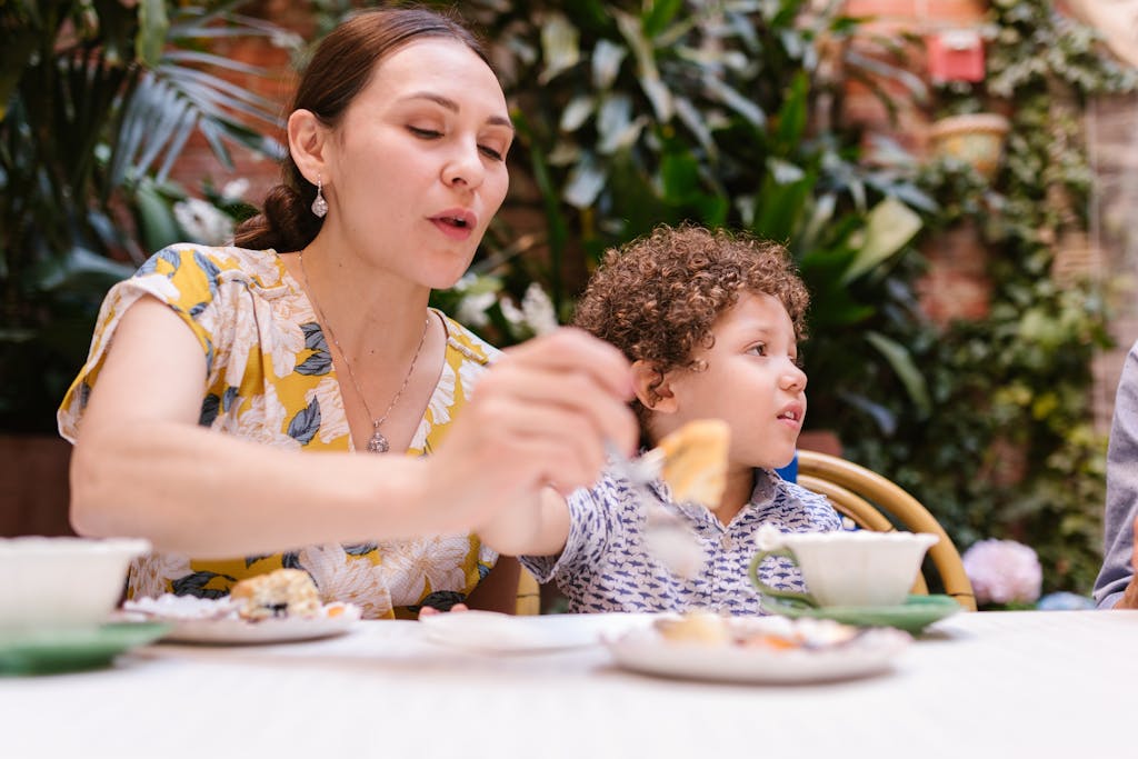 A mother and her young son sharing a delightful meal outdoors in a garden setting.
